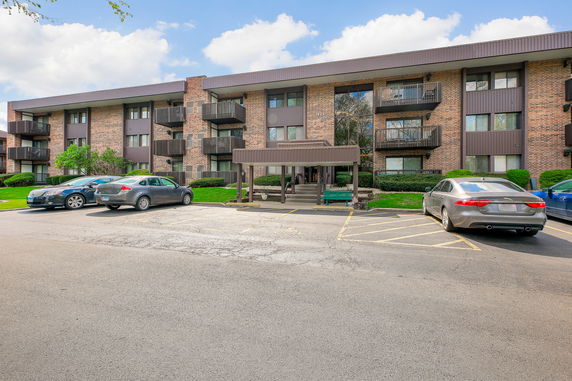 Front view of a multi-story brick apartment building with balconies.