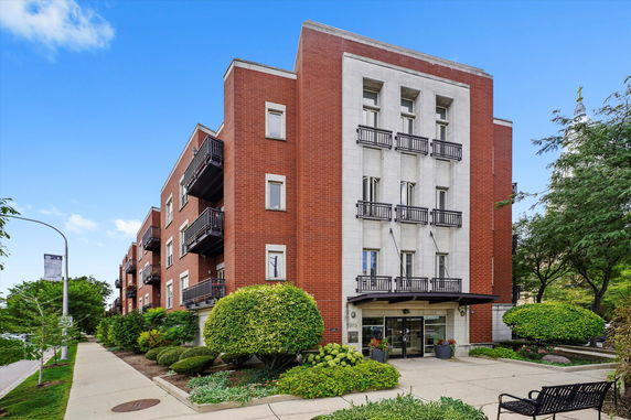 Front view of a multi-story brick apartment building with balconies.