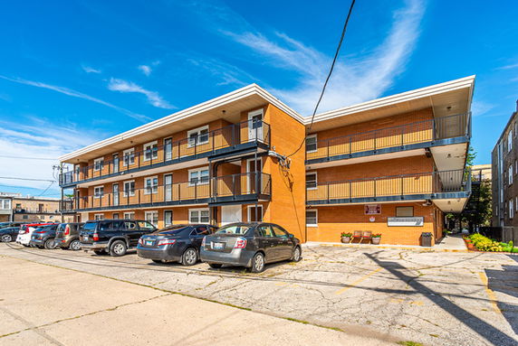 Front view of a multi-story brick apartment building with external staircases.