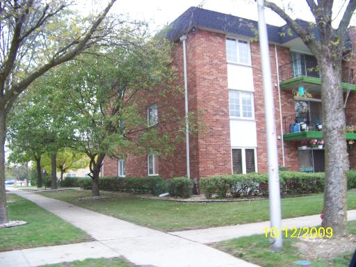 Front view of a multi-story brick apartment building with balconies.
