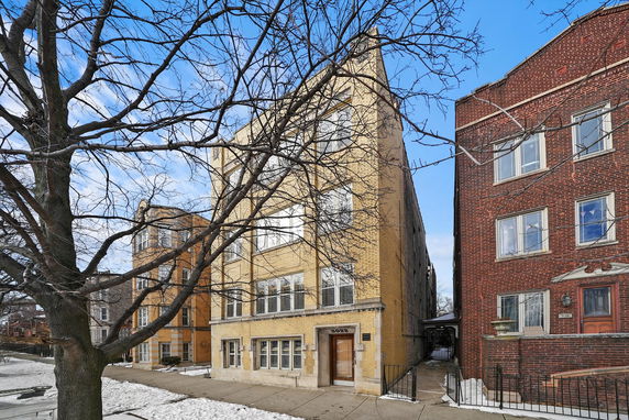 Front view of a multi-story brick apartment building with large windows.