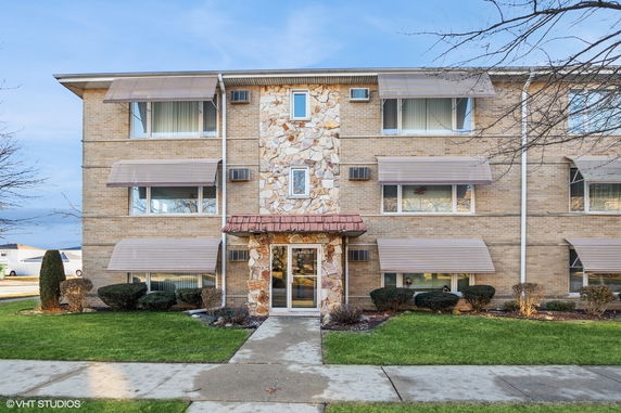 Front view of a multi-story residential building with stone entrance facade.