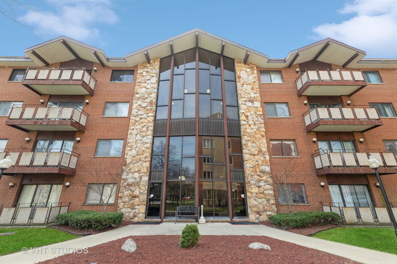Front view of a multi-story residential building with balconies and a central glass facade.