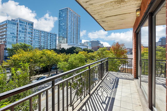 View from a balcony overlooking neighboring high-rise buildings and trees.