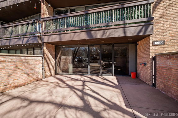 Front view of a brick building with two balconies and a glass entrance.
