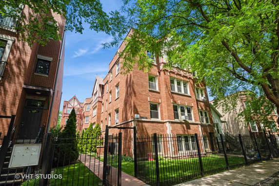 Front view of a multi-story brick building with windows and a gated entrance.