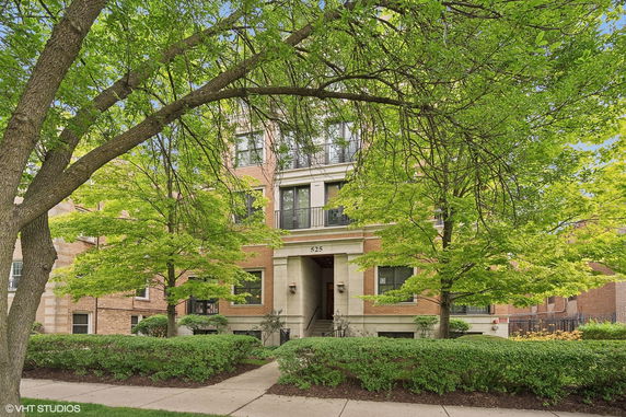 Front view of a multi-story brick building with trees and greenery in front.