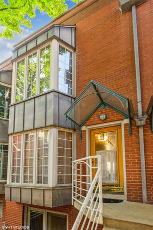 Front view of a multi-story brick building with bay windows and a glass canopy over the entrance.