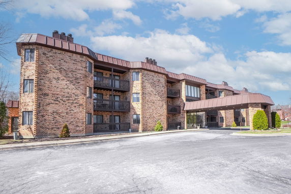 Front view of a multi-story brick apartment building with balconies.