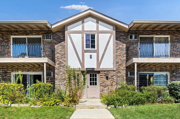 Front view of a two-story house with brick facade and balconies.