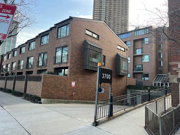 Front view of a brick multi-story residential building with balconies.