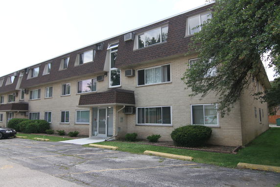 Front view of a multi-story apartment building with multiple windows and a main entrance.