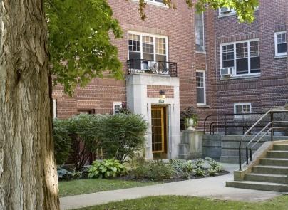 Front view of a multi-story brick building with a central entrance and steps leading up to it.