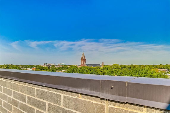 Panoramic view from a rooftop overlooking a city with a church steeple visible in the distance.