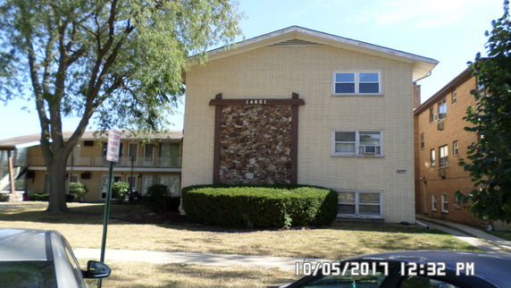 Front view of a multi-story brick building with a decorative stone wall in the center.
