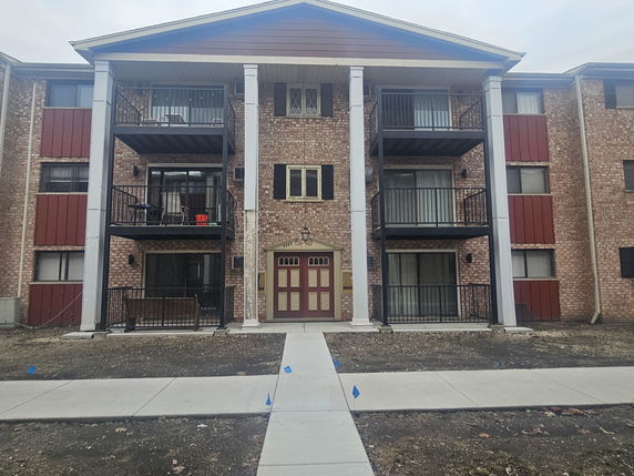 Front view of a multi-story apartment building with balconies.