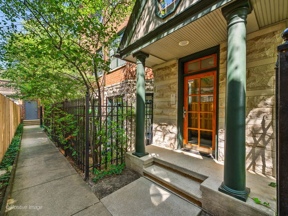Front view of a house entrance with stone exterior and green columns.