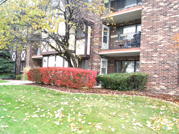 Front view of a multi-story brick apartment building with balconies.