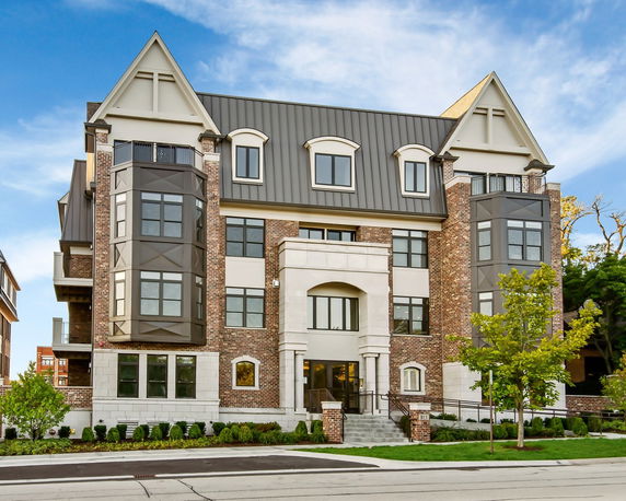 Front view of a multi-story building with a gabled roof and large windows.