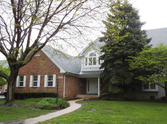 Front view of a single-story house with a brick facade and a large gable roof.