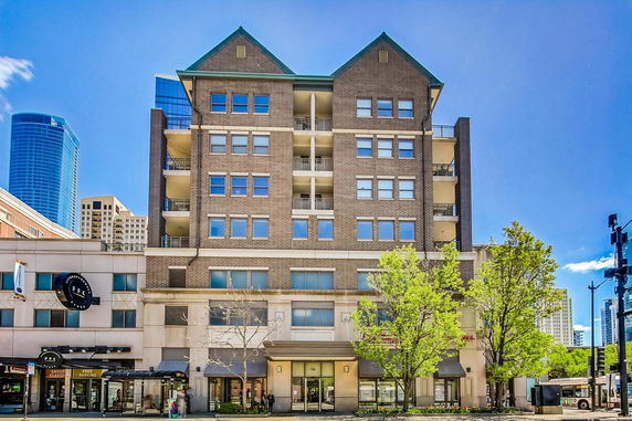 Front view of a multi-story brick building with balconies and a peaked roof.