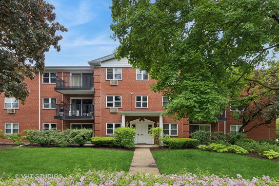 Front view of a three-story brick building with balconies.