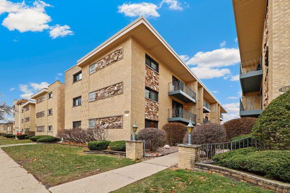 Front view of a three-story apartment building with balconies and brick facade.