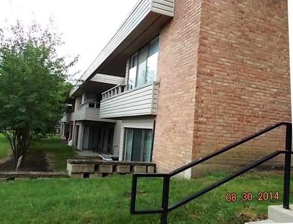 Side view of a multi-story brick apartment building with balconies.