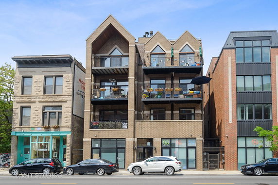 Front view of a multi-story building with balconies and a gabled roof.