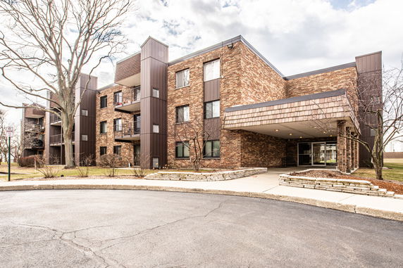 Front view of a multi-story brick apartment building with balconies and an entrance.