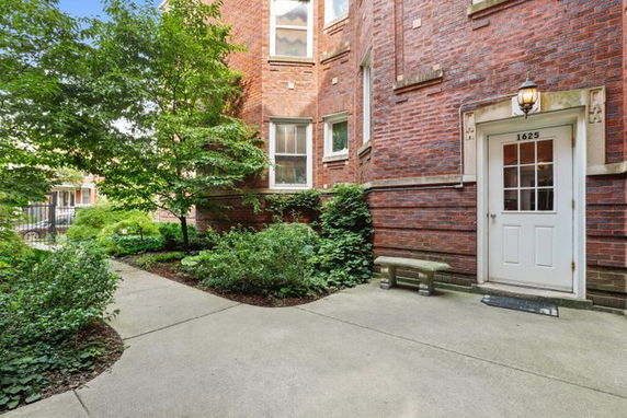 Front view of a brick building with a small entrance and surrounding greenery.