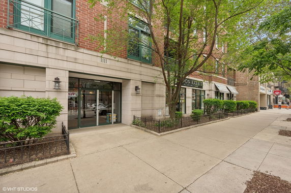 Front view of a multi-story building with large glass windows and brick facade.