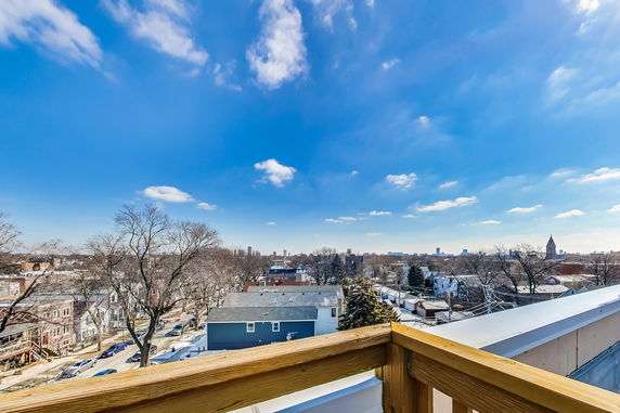 Panoramic view from a rooftop overlooking a suburban residential area with distant city skyline.