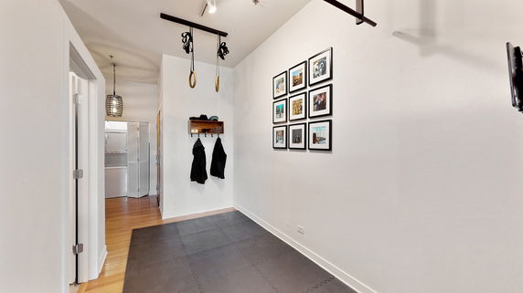 Room with gymnastic rings hanging from the ceiling and a padded floor section.