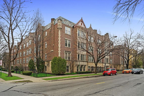 Front view of a multi-story brick apartment building on a street corner.