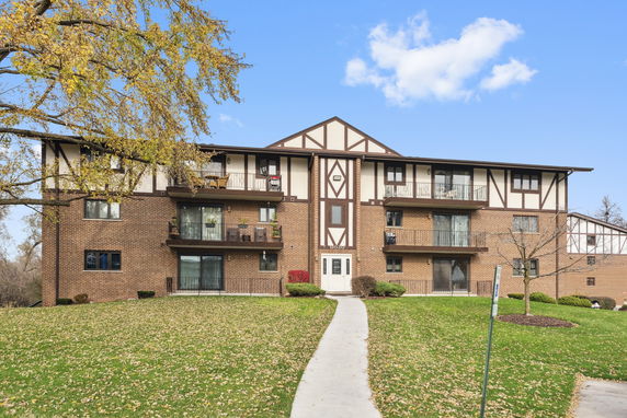 Front view of a multi-story brick apartment building with balconies.