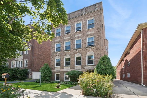 Front view of a four-story brick building with decorative details above the windows.