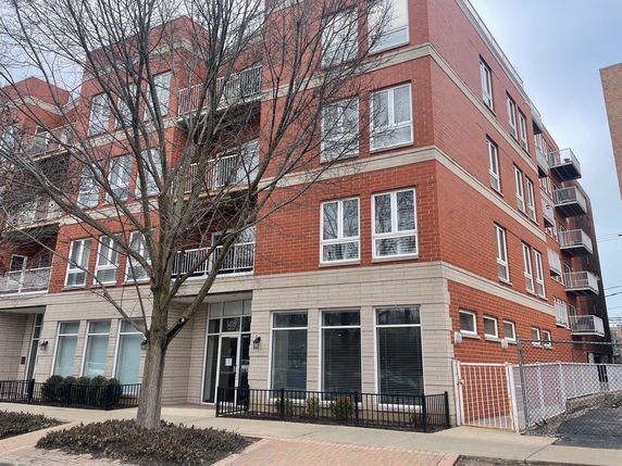 Front view of a multi-story brick apartment building with balconies.