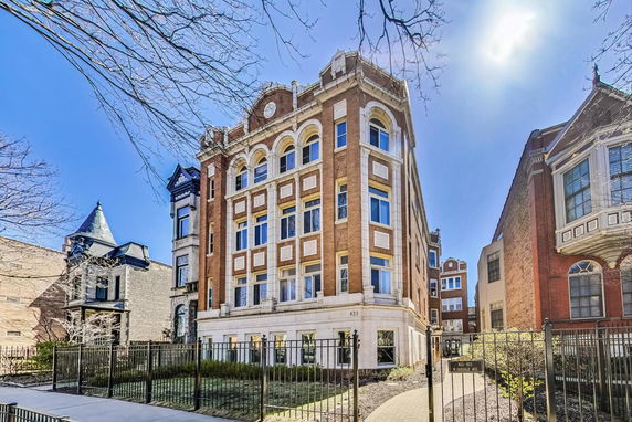 Front view of a multi-story brick building with arched windows and decorative trim.