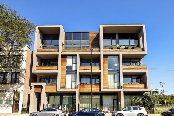 Front view of a modern multi-story building with large windows and balconies.