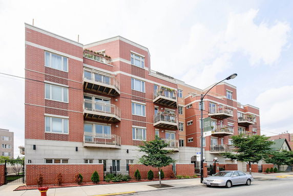 Front view of a multi-story brick apartment building with balconies.