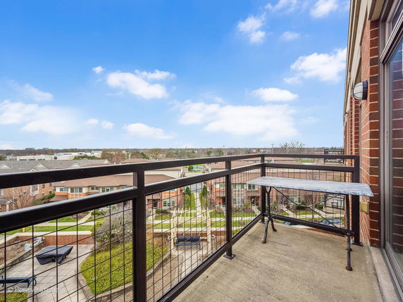 Aerial view from a balcony overlooking a residential area with houses and greenery.