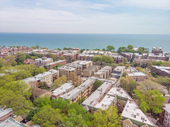 Panoramic view of a residential area with multiple buildings and the sea in the background.