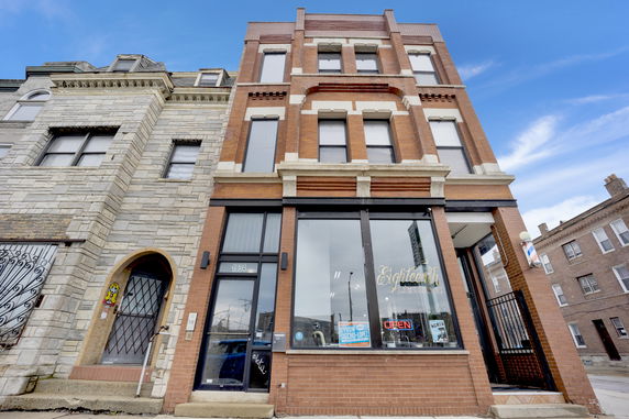 Front view of a multi-story brick building with large windows.