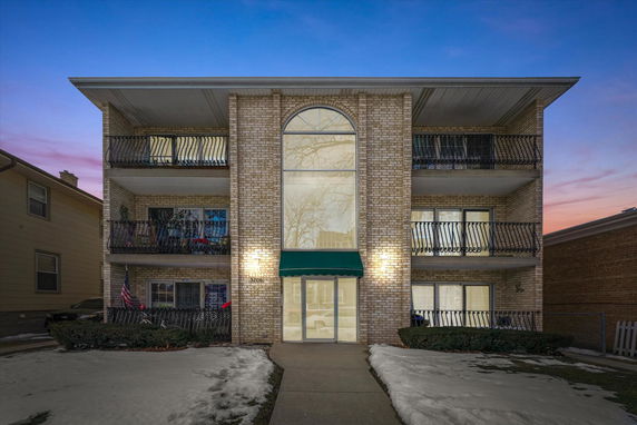 Front view of a three-story building with balconies and a large central window.
