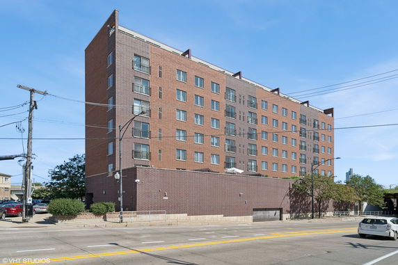 Front view of a multi-story brick apartment building with numerous windows and small balconies.