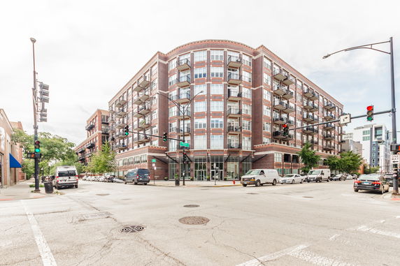 Front view of a multi-story apartment building with balconies and large windows.