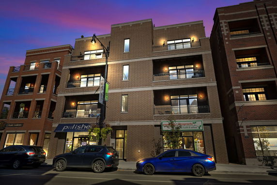 Front view of a multi-story brick building with balconies and a storefront on the ground level.