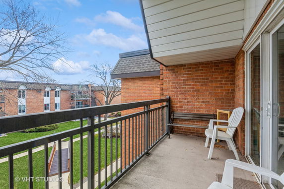 View from a balcony overlooking a courtyard between brick apartment buildings.
