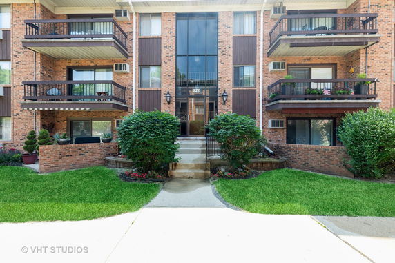 Front view of a multi-story residential building with balconies and a central entrance.